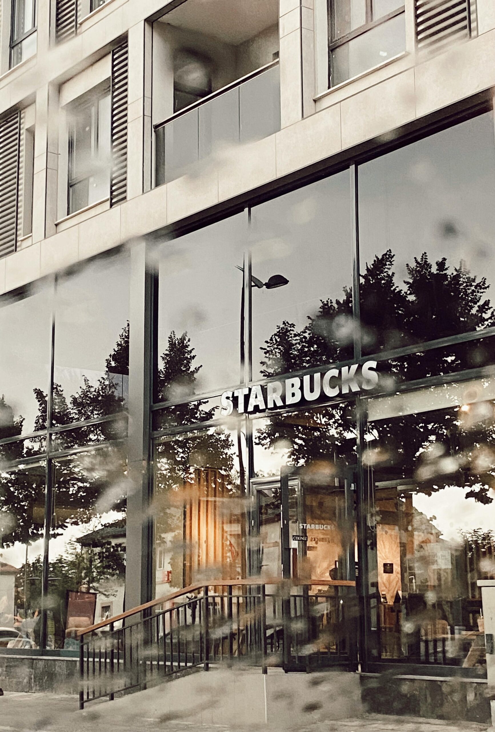 Contemporary Starbucks facade showcasing glass windows and exterior reflections on a rainy day.